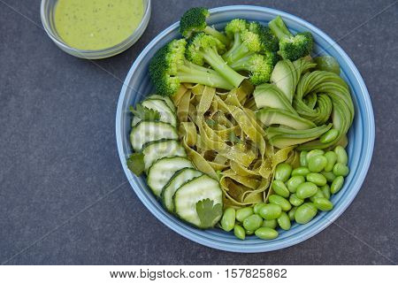 Spinach pasta with cucumber, broccoli, avocado and edamame