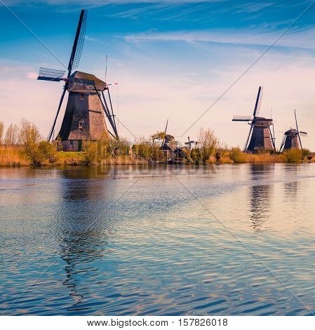 Sunny spring scene in the canal in Netherlands. Dutch windmills at Kinderdijk an UNESCO world heritage site. Tipical Holland landscape.