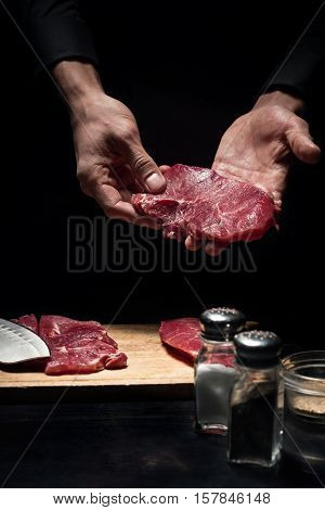 Good receipt. Close up of chefs hands holding meat while cooking and working in reastaurant.
