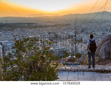 Athens, Greece - October 15, 2016: Man looking Athens skyline and sunset from Lykavittos hill, Athens, Greece
