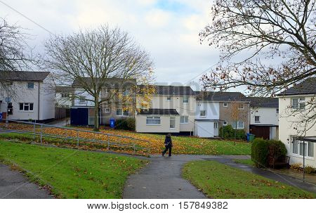 Bracknell,England - November 22, 2016: A pedestrian passes in front of homes on an English housing estate in Bracknell, England on a wet afternoon in November