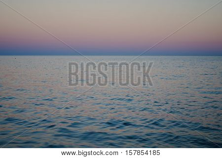 Seascape of water and horizon after sunset blue and pink colors