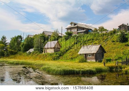 north Russian village Isady. Summer day Emca river old cottages on the beach
