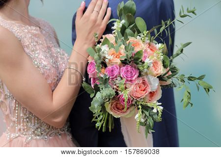 Beautiful bridal bouquet in hands of the bride. Wedding bouquet of peach roses  single-head pink rose aqua eucalyptus ruscus gypsophila