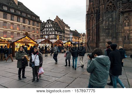 Best Christmas MArket atmosphere in Strasbourg Alsace with people buying gifts drinking mulledwine in central Place near Notre-Dame Cathedral