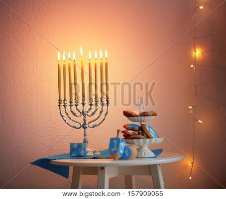 Menorah, dreidels and cookies for Hanukkah on stool in living room