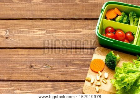 lunch box for kid with fresh vegetables on wooden background.