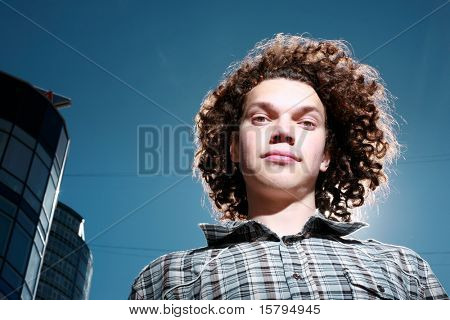 Portret van een funky jongeling met krullend haar buiten.