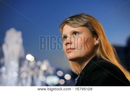 Menina loira bonita sobre o céu azul, pôr do sol