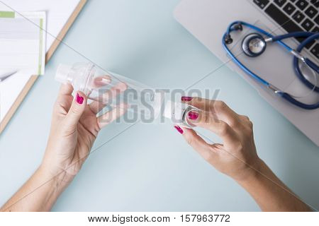 Top view of hands of a female doctor are inserting a pressurized cartridge inhaler into an inhalation chamber on a medical demonstration on her desk - Medical respiratory disease - Focus on the chamber