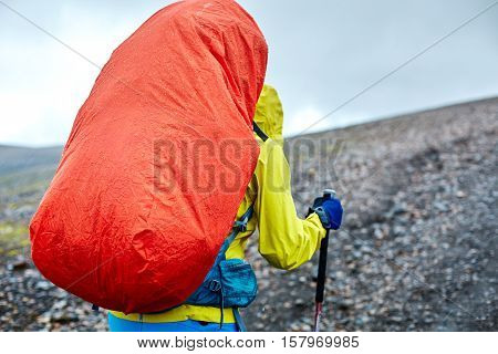 woman hiker on the trail in the Islandic mountains. Trek in National Park Landmannalaugar, Iceland. woman walking in the rain with a backpack in a raincoat and wearing a waterproof jacket