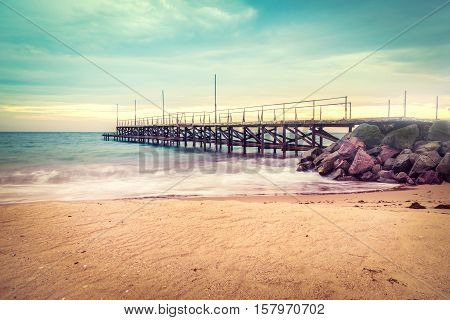 Sunset over the sea bridge in Ravda Bulgaria. Slow motion effect. Old rusty pier against the sunset rays.