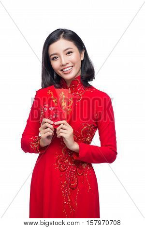 Portrait of a beautiful Asian woman on traditional festival costume Ao Dai holding red pocket - lucky money. Tet holiday. Lunar New Year.