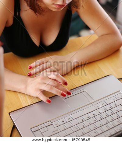 Mladá žena psaní na přenosném počítači doma.