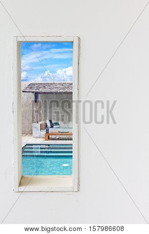White wall window with swimming pool view vertical landscape concept background.
