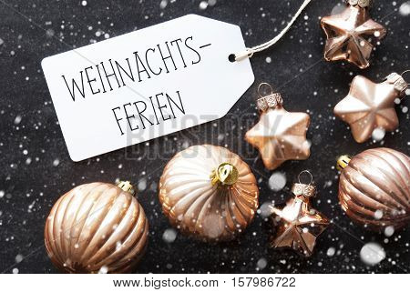Label With German Text Frohe Weihnachten Means Merry Christmas. Bronze Christmas Tree Balls On Black Paper Background With Snowflakes. Christmas Decoration Or Texture. Flat Lay View