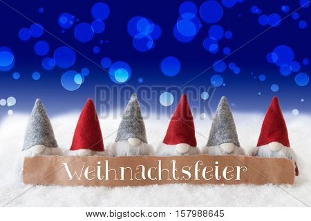 Label With German Text Weihnachtsfeier Means Christmas Party. Christmas Greeting Card With Gnomes. Sparkling Bokeh And Blue Background With Snow.
