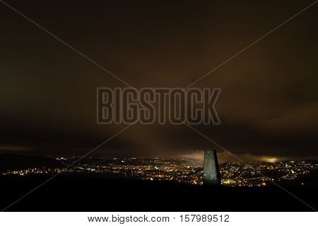 Trig point on Little Solsbury Hill overlooking Bath. Night view of the UNESCO World Heritage City of Bath with stone used for cartographic triangulation in foreground