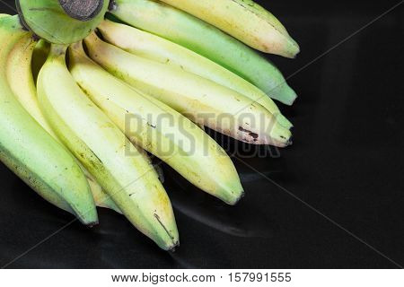Cavendish bananas on black granite table background.