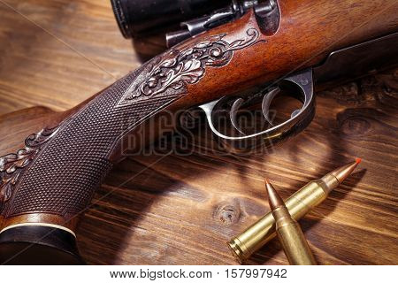 Sniper rifle with bullets on the wooden background