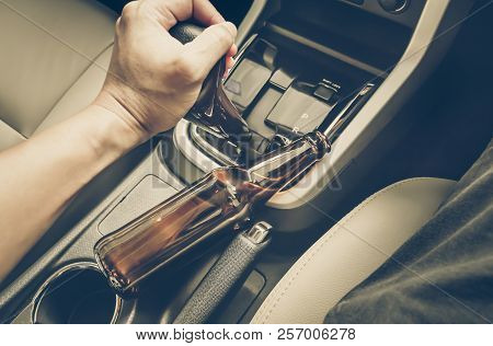 A Driver Holding Alcoholic Bottle While Driving / Drunk Driving Concept