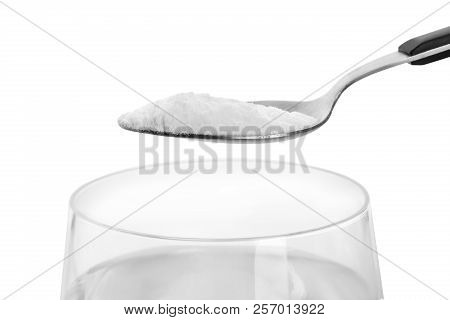 Spoon With Baking Soda Over Glass Of Water On White Background