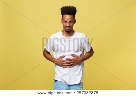 Closeup Portrait Of Miserable, Upset, Young Man, Doubling Over In Stomach Pain, Looking Very Sick Un