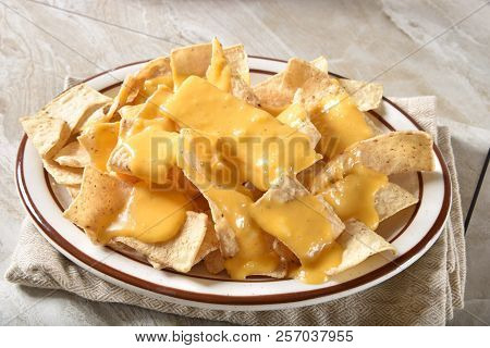 A Plate Of Corn Tortilla Strips With Creamy Cheddar Cheese Sauce