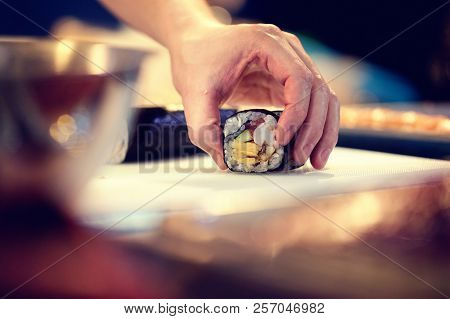 Japanese chef at work preparing delicious sushi roll