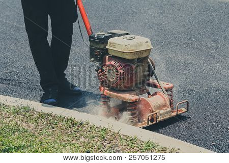 Worker Uses Vibratory Plate Compactor Compacting Asphalt At Road Repair
