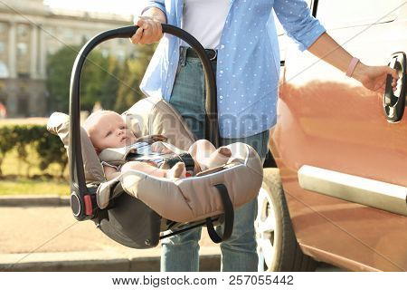 Mother Holding Child Safety Seat With Baby Near Car Outdoors