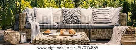 Cushions On Settee And Rattan Table On Patio In The Garden During Summer. Real Photo