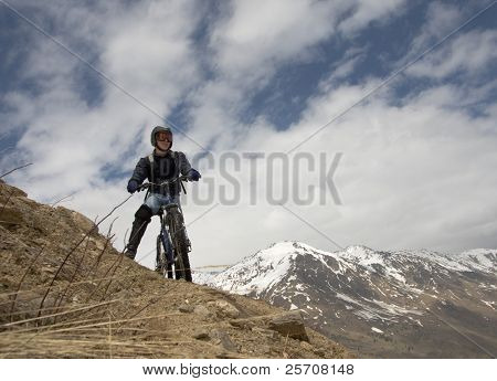 Mountain biker na skalnatém vrcholu proti obloze