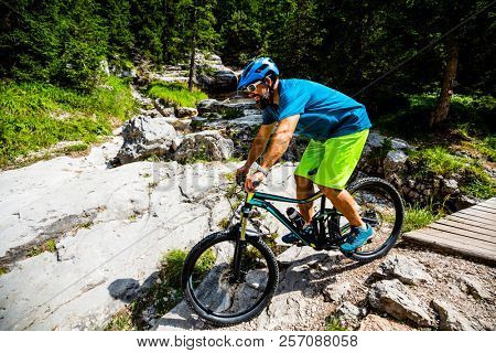 Tourist cycling in Cortina d'Ampezzo, stunning rocky mountains on the background. Man riding MTB enduro flow trail. South Tyrol province of Italy, Dolomites.