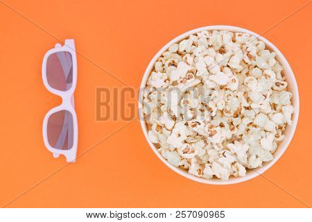 3d Glasses And A Paper Cup With Popcorn Are Isolated On A Orange Background, A View From Above.flat 