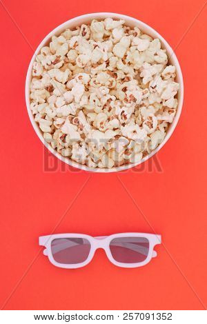 3d Glasses And A Paper Cup With Popcorn Are Isolated On A Red Background, A View From Above.flat Lay