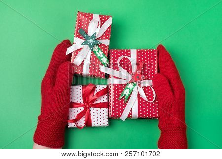 Female Hands Holding Christmas Fifts In Red Mittens Holiday Card Background Flat Lay Top View Red Gr