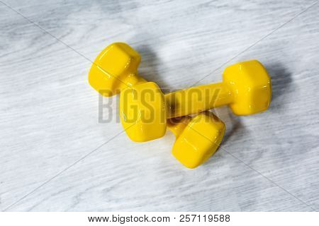 Yellow Modern Dumbbells On A Wooden Floor