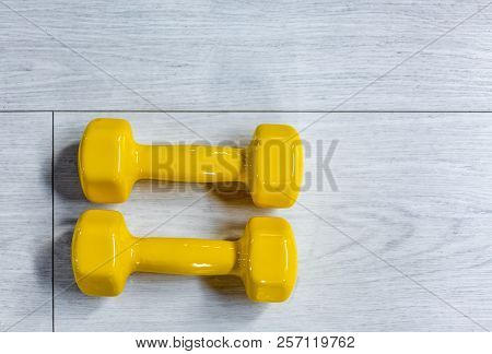 Yellow Modern Dumbbells On A Wooden Floor