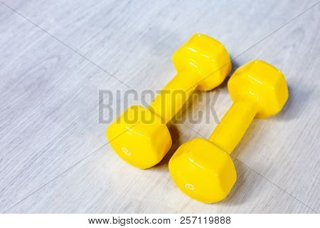 Yellow Modern Dumbbells On A Wooden Floor