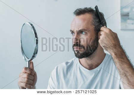 Bearded Middle Aged Man Combing Hair And Looking At Mirror, Hair Loss Concept