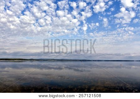 Bright Clouds Reflected In The Water, South Ural Lake Uvildy, In The Distance Are Seen The Ural Moun