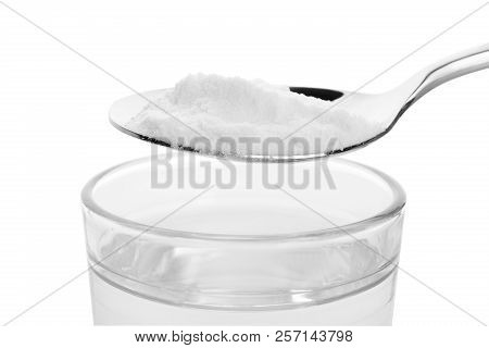 Spoon With Baking Soda Over Glass Of Water On White Background