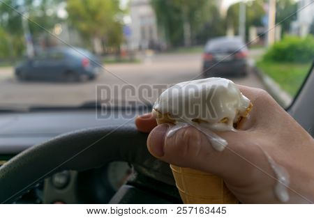 The Driver Holds The Ice Cream While Driving A Car