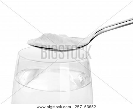 Spoon With Baking Soda Over Glass Of Water On White Background