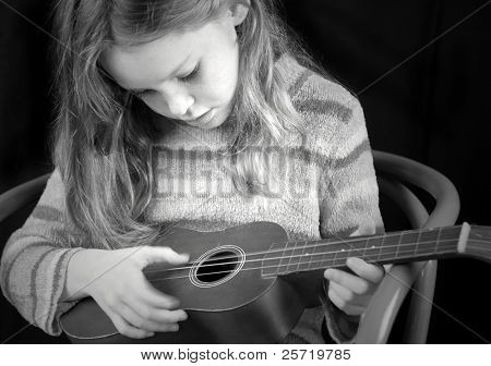 Young girl strumming acoustic instrument