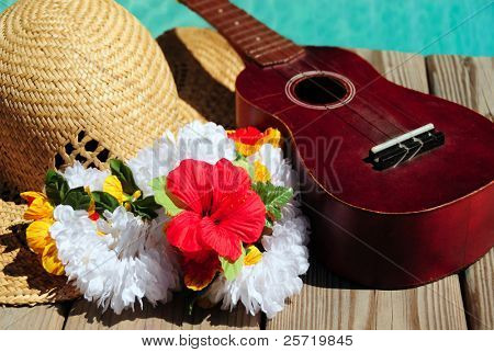 Cappello di paglia e ukulele e lei sul molo accanto all'acqua