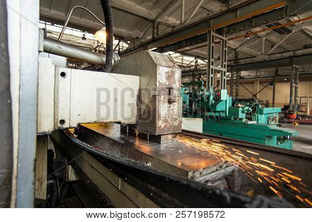 Metal Parts On A Flat Grinder Are Treated With An Abrasive Wheel, Sparks Fly From Under The Circle, 