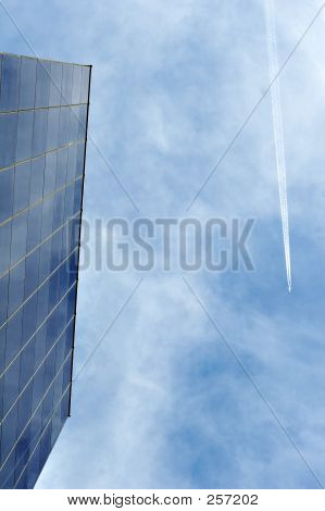 Glas kantoorgebouw met vliegtuig en blauwe hemel