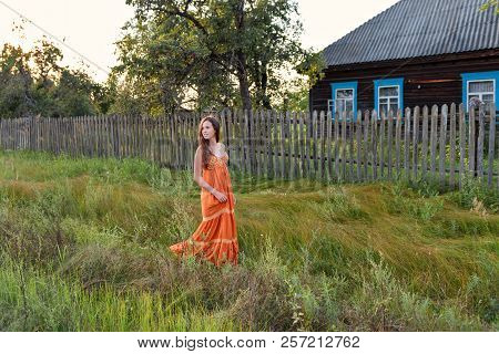 At The Late In The Evening A Young Woman In A Retro Village Attire Strolls Along The Old Stockade An
